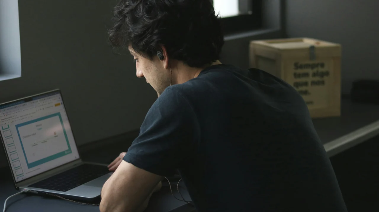 Profissional trabalhando em um notebook, com foco nas mãos e na tela.