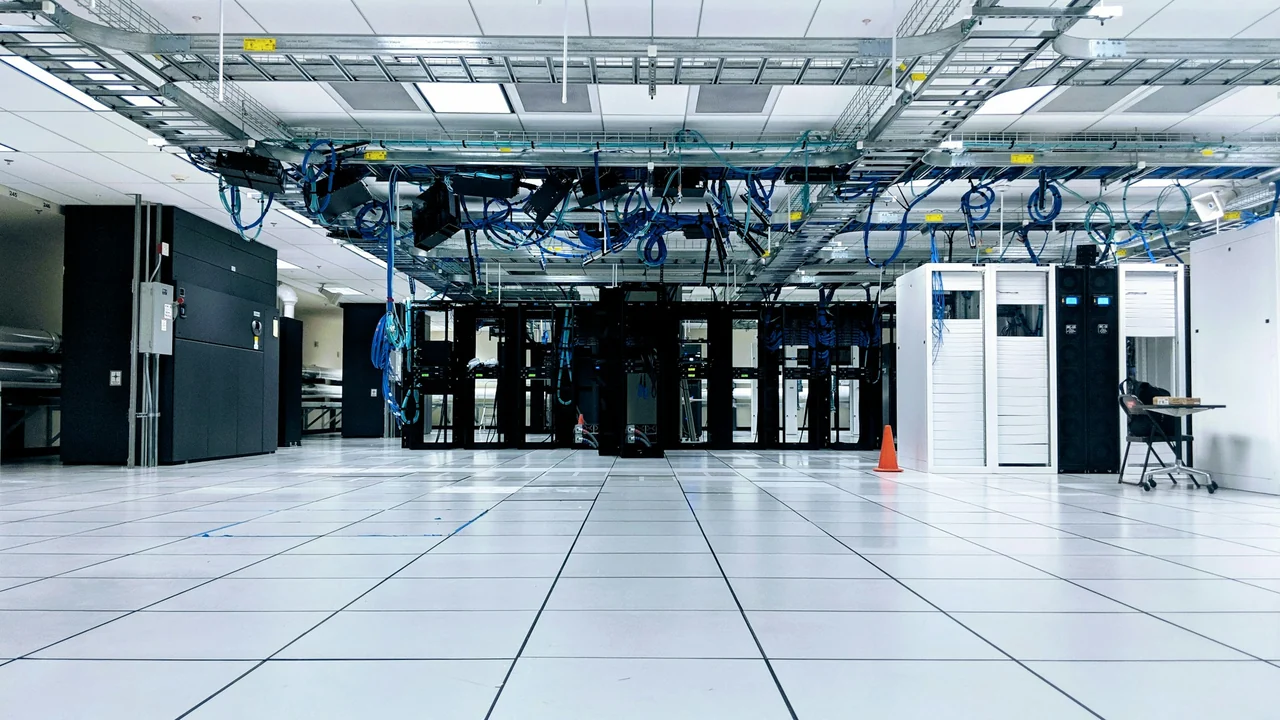 Corredor de datacenter com armários de servidores e infraestrutura de rede.